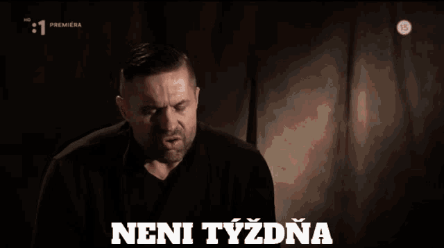 a man in a black shirt is making a funny face in front of a sign that says " nenityzdna "