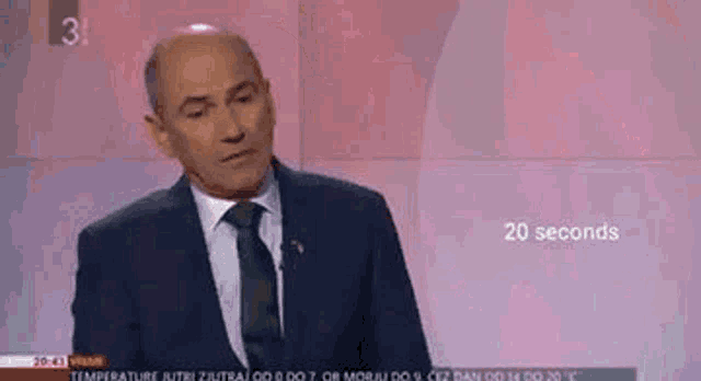 a man in a suit and tie is giving a speech on a television channel .