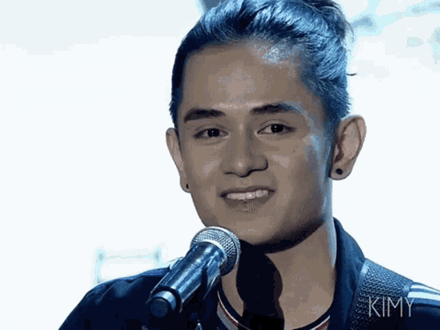 a young man singing into a microphone with kimy written on the bottom of his shirt