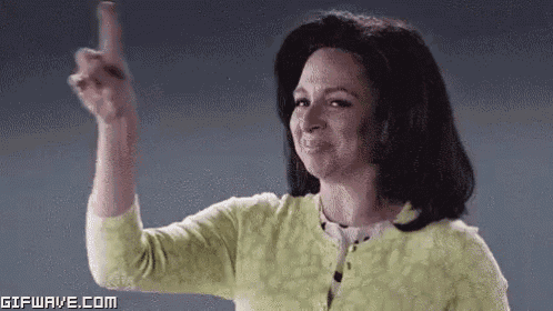 a woman in a green sweater is pointing her finger at the camera .