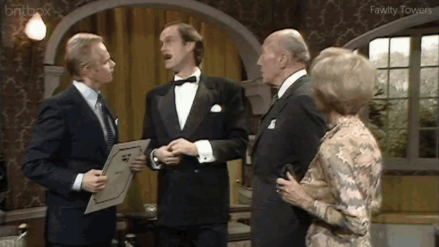 a man in a tuxedo is holding a piece of paper in front of two other men