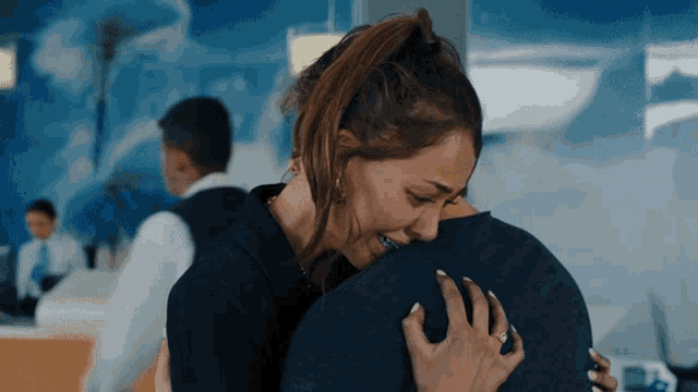 a woman is hugging a man in a blue shirt