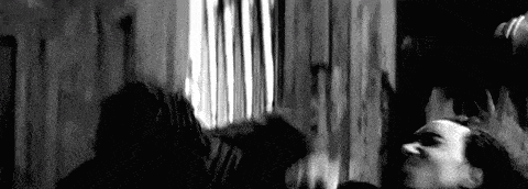 a black and white photo of a man standing next to a woman in a room .