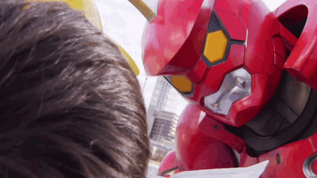 a close up of a red robot looking at a person 's head