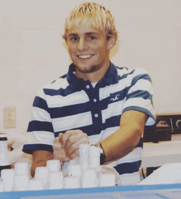 a man wearing a blue and white striped shirt with a hollister logo