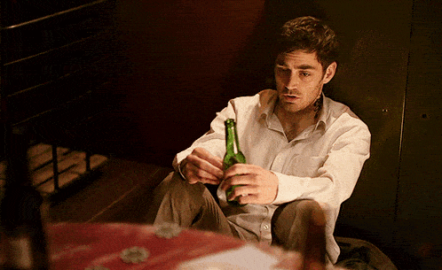 a man in a white shirt holds a green bottle in his hands