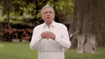 a man in a white shirt is holding a rosary in his hands while standing in front of a tree .