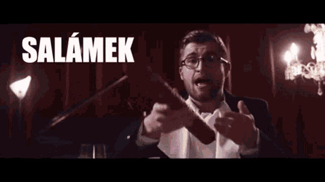 a man in a suit holds a sausage in front of a sign that says salamaek