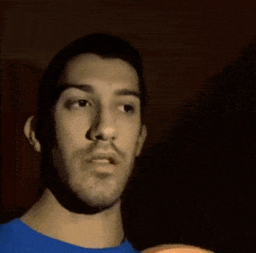 a man wearing sunglasses and a blue shirt is looking at the camera .