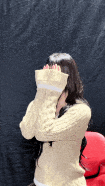 a woman in a tan sweater covering her face with her arms