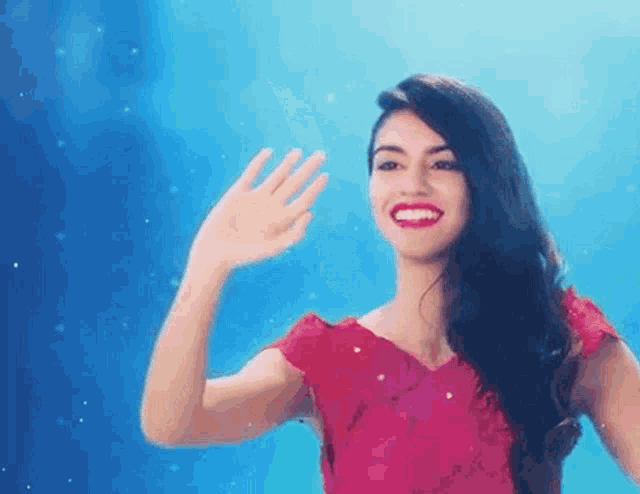 a woman in a pink dress is waving her hand in the air .