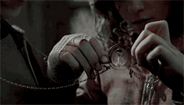a close up of a person holding a necklace in their hands .
