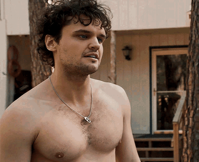 a shirtless man wearing a necklace with a key pendant on it