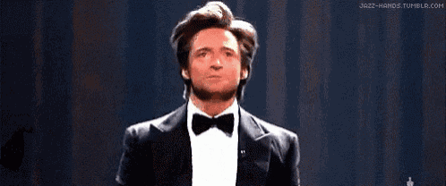 a man in a tuxedo and bow tie is holding his arms out and saying iiipm