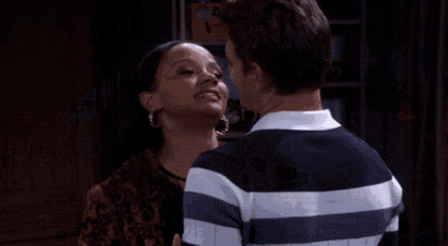 a man in a striped shirt is kissing a woman