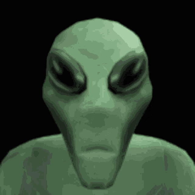 a close up of a green alien 's face with black eyes on a black background .
