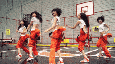 a group of women are dancing on a basketball court in front of a sign that says " do not enter "
