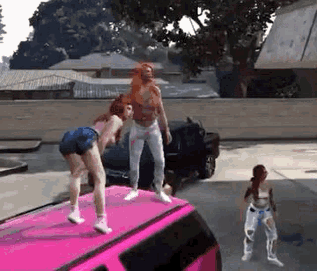 two women are dancing on the roof of a pink van .