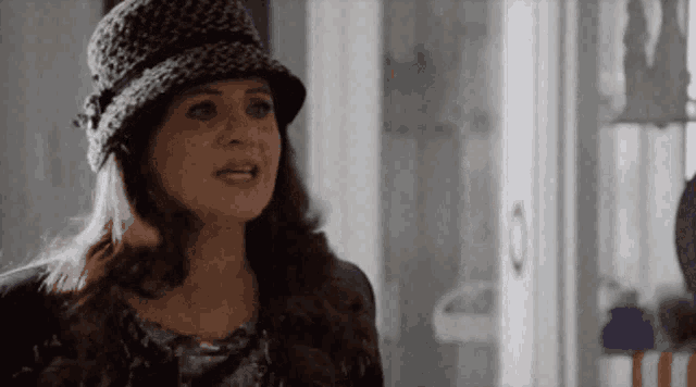a woman wearing a leopard print hat is standing in front of a door
