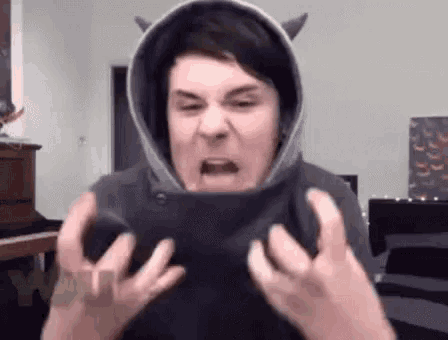 a man is wearing a hoodie with horns on it and making a funny face .