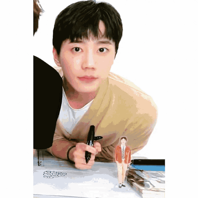 a young man in a yellow sweater is holding a pen