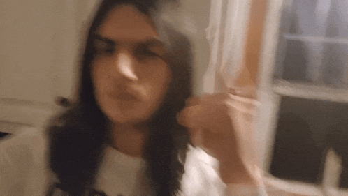 a blurry picture of a woman with long hair standing in front of a window ..