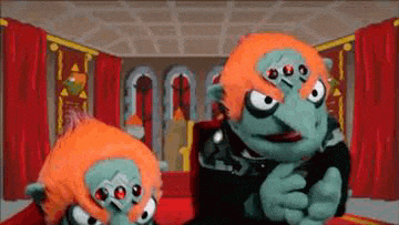 a couple of stuffed animals are standing in a room with red curtains