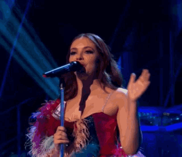 a woman is singing into a microphone on a stage