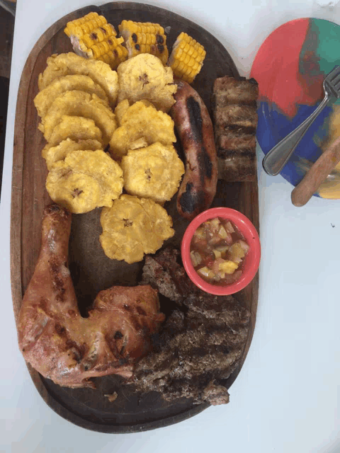 a wooden cutting board filled with a variety of food including corn and plantains