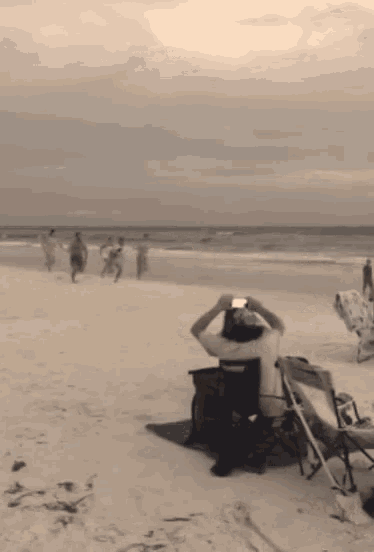 a person sitting on a beach taking a picture