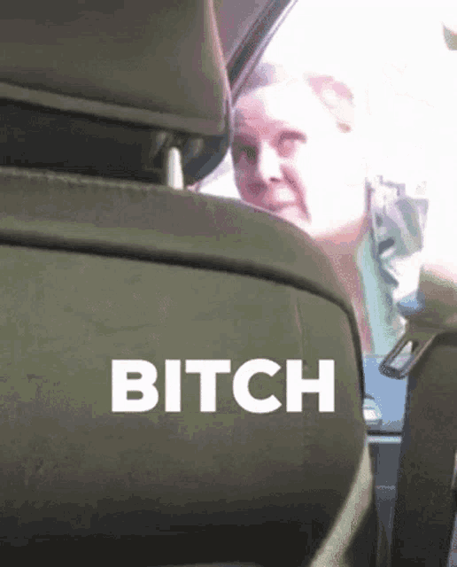 a woman sitting in the back seat of a car with the word bitch on the back seat