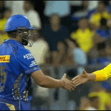 a cricket player is shaking hands with another cricket player during a game .