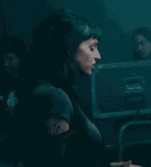 a woman is sitting in front of a computer monitor in a dark room .