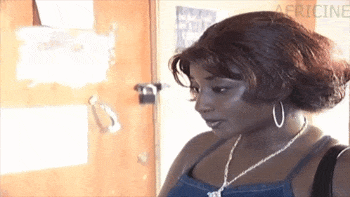 a woman wearing hoop earrings and a necklace is standing next to a door .