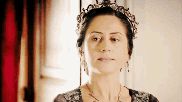 a woman wearing a tiara and a necklace looks to the side
