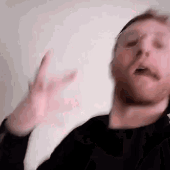 a man with a beard and mustache is making a funny face with his hands .