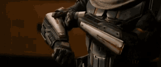 a man in a helmet and armor is standing in a room adjusting his helmet .