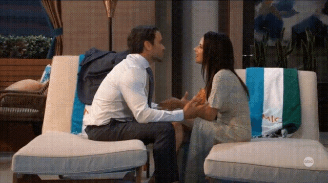 a man and a woman are sitting on a chair with a towel that says mic on it