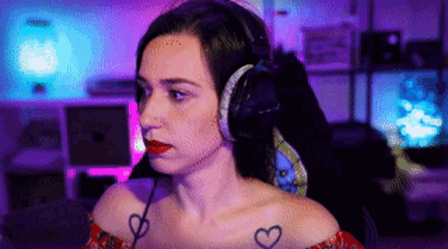 a woman with a heart tattoo on her shoulder is wearing headphones