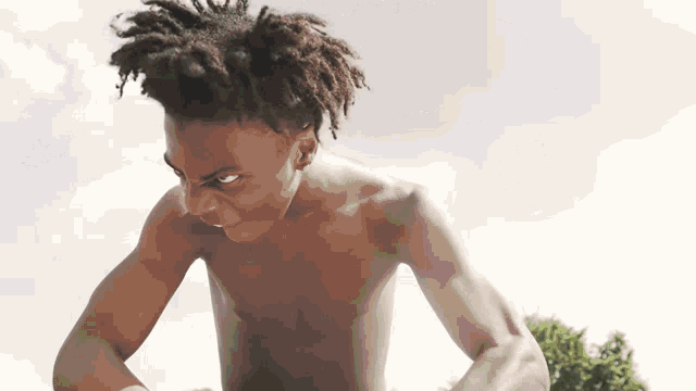a shirtless man with dreadlocks is looking at the camera .