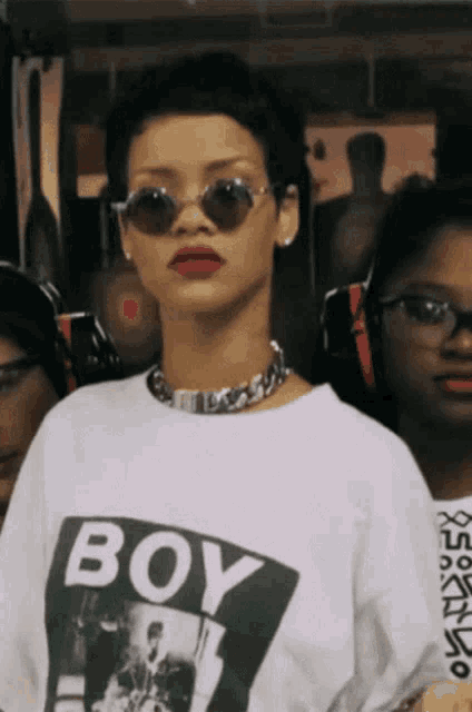 a woman wearing sunglasses and a white shirt that says boy