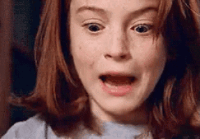 a close up of a little girl making a surprised face .