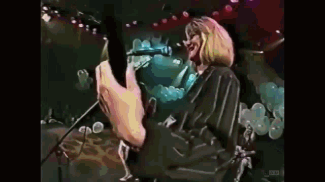 a woman is singing into a microphone while holding a guitar on a stage .