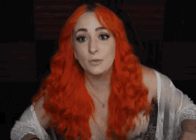 a woman with long red hair is wearing a white top