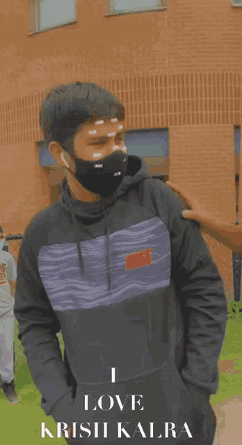 a man wearing a mask and a sweatshirt that says i love crisis kalra