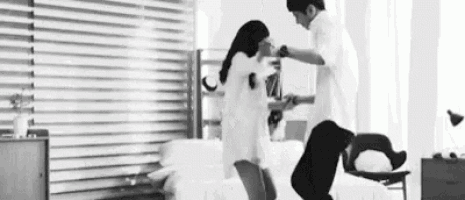 a man and a woman are dancing in a living room in a black and white photo .