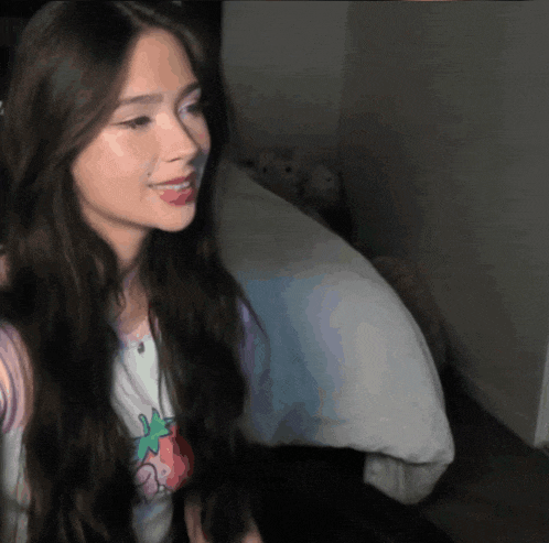 a woman with long dark hair is wearing a strawberry shirt