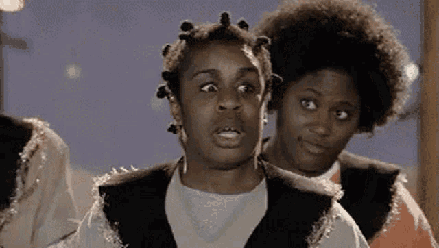 a group of women are standing next to each other and one of them is making a funny face .