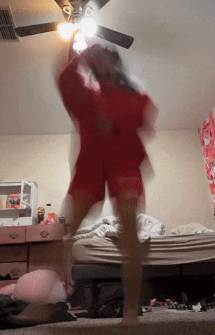 a blurry picture of a person dancing in a bedroom with a ceiling fan