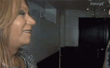 a woman is smiling in front of a door and the word travagif is on the bottom